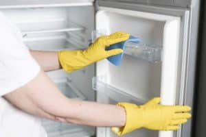 woman with rubber gloves cleaning fridge 23 2148465044