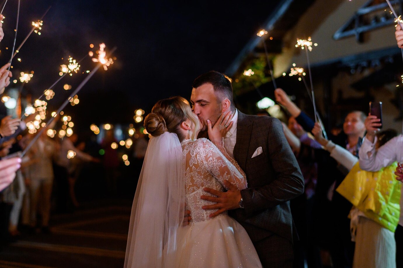 side view beautiful bride bridegroom which hugging kissing each other while guests holding cold sparkles which burning creating glowing arch night ceremony outdoor 8353 12110