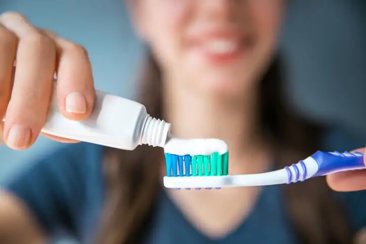 toothpaste being placed on toothbrush